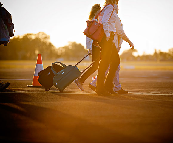 People walking luggage sunset airport