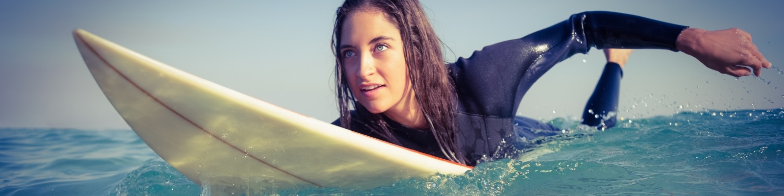 Person wearing a wetsuit swimming on a surfboard